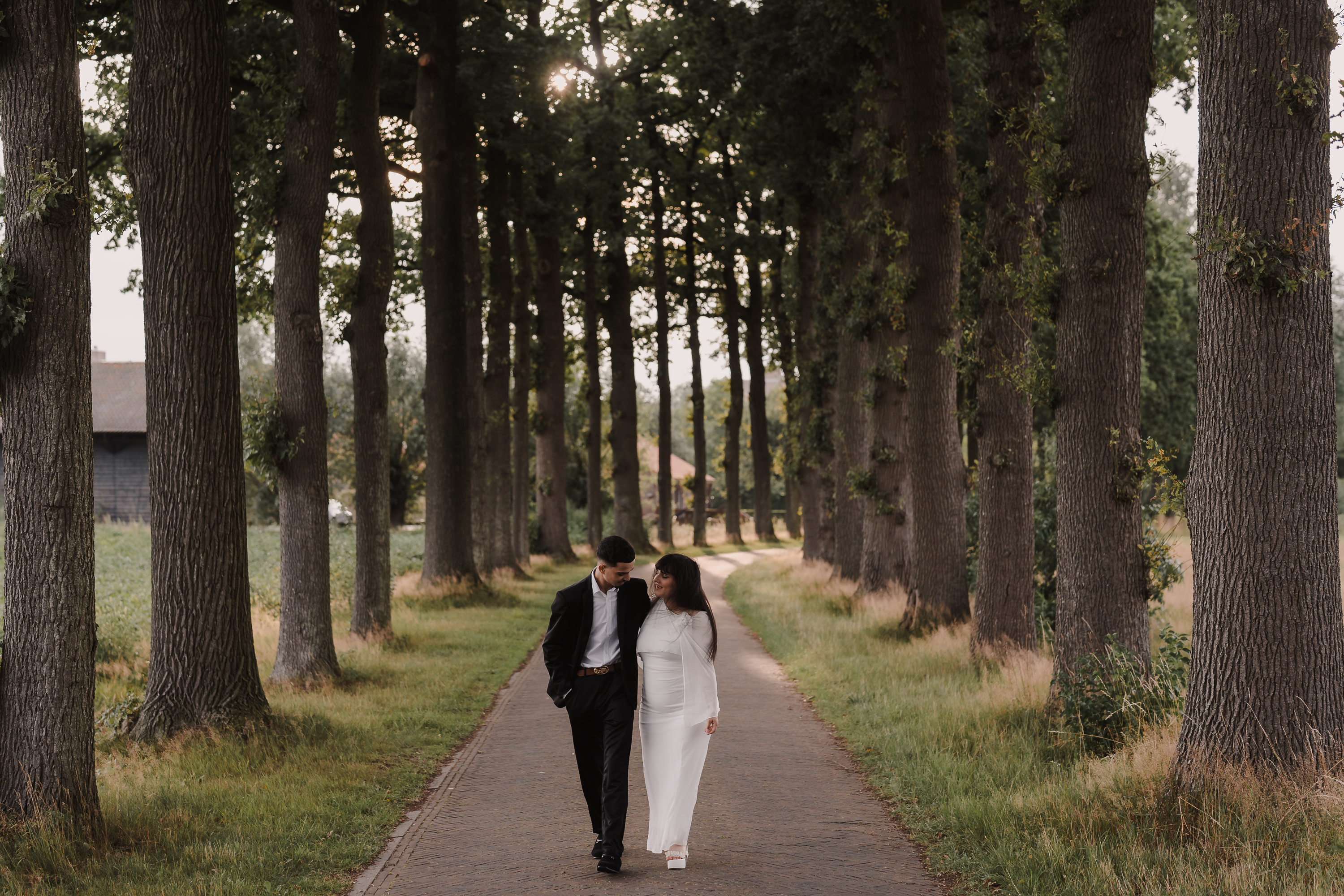 Bride and groom walking hand-in-hand along a tree-lined countryside road near Amersfoort, captured by Photos by Ville, wedding photographer in the Netherlands for international and expat couples