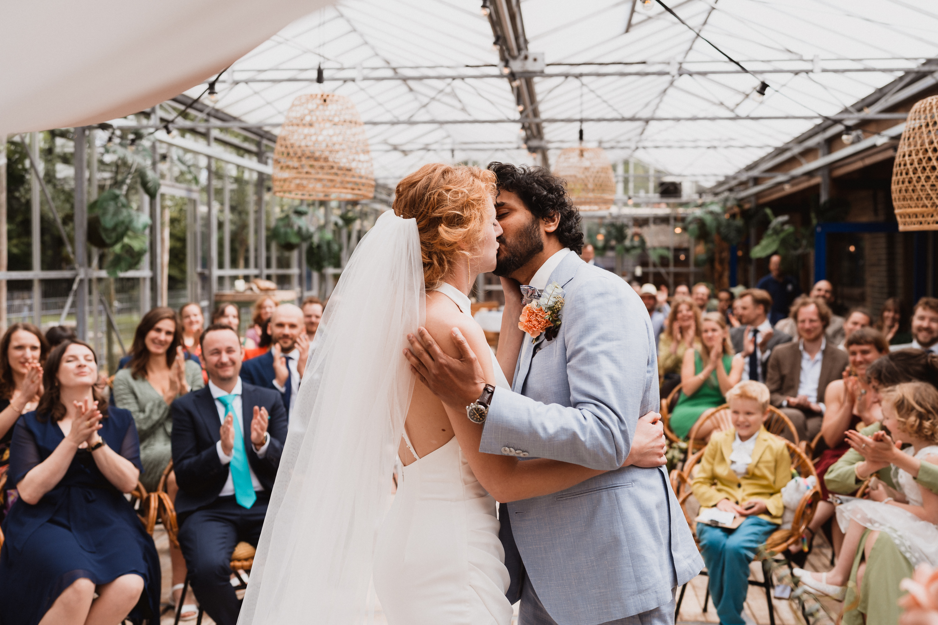 Bride and groom share their first kiss as a married couple during the wedding ceremony at Brasserie Park in Leiderdorp, captured by Photos by Ville, wedding photographer in the Netherlands for international couples