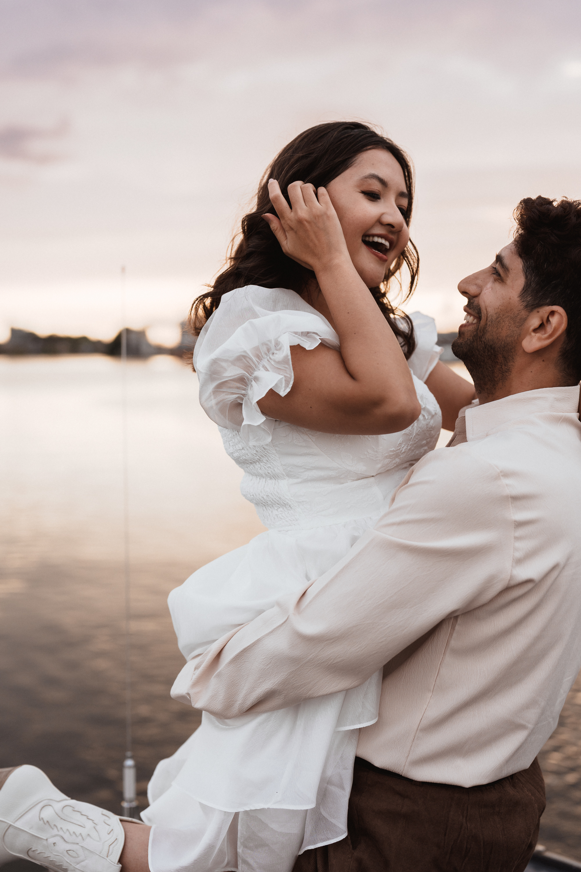 Groom holding his bride in his arms during a relaxed boat moment in Zaandam, captured by Photos by Ville, wedding photographer in the Netherlands for international and expat couples