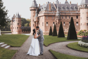 Bruidspaar kust romantisch voor de imposante façade van Kasteel de Haar tijdens trouwfotografie