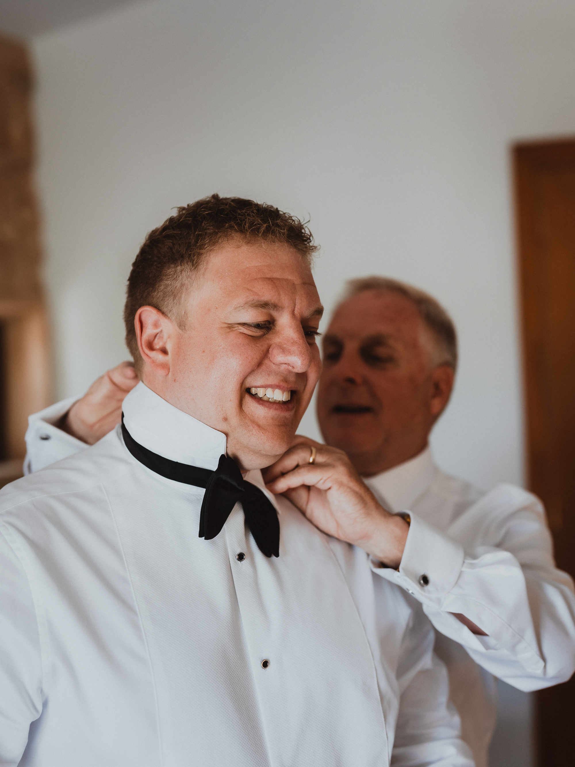Father helping the groom with his bow tie before the wedding at Finca Son Mir Mallorca, photographed by Photos by Ville