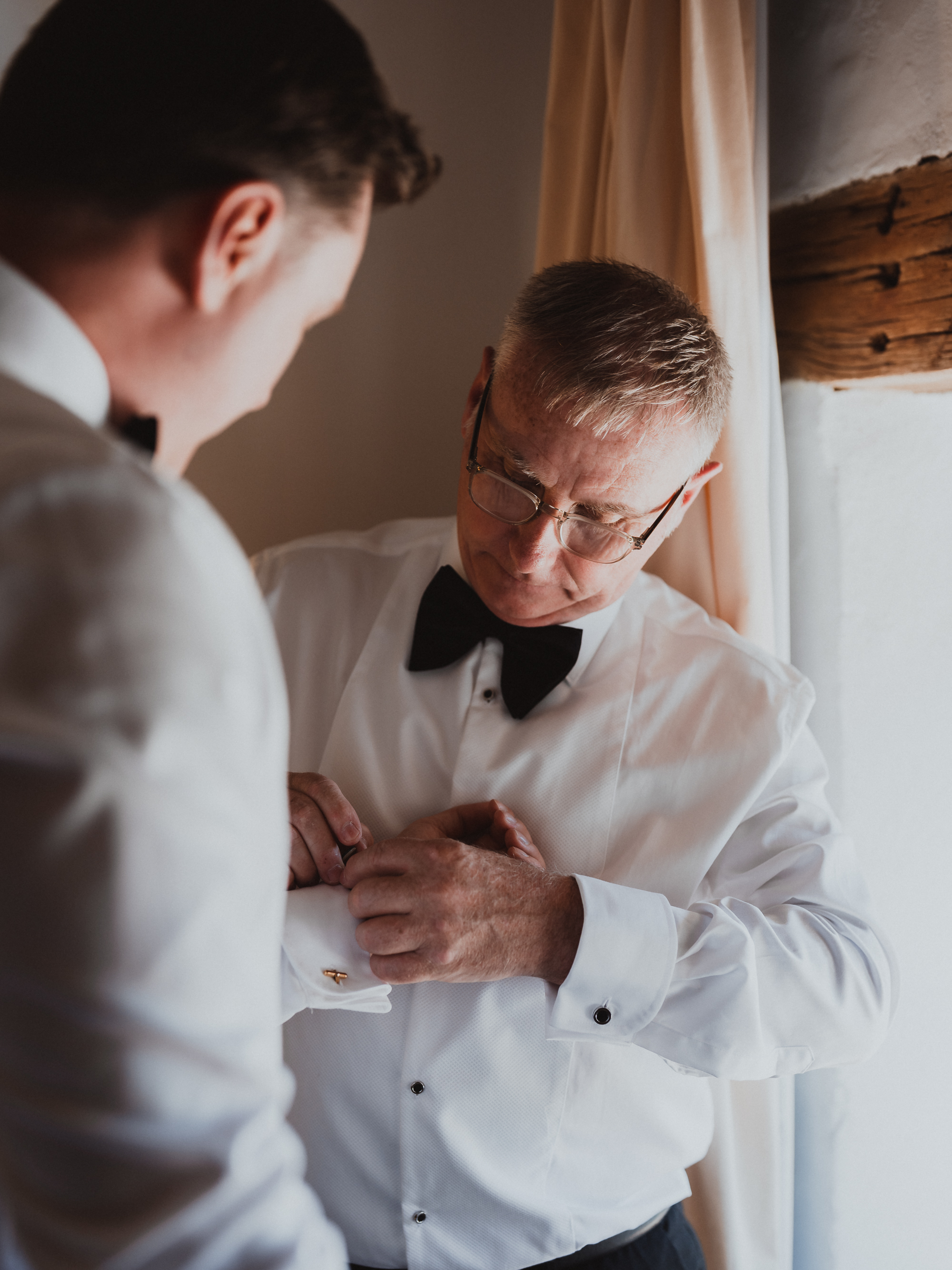 Father adjusting cufflinks for the groom during wedding preparations in Mallorca