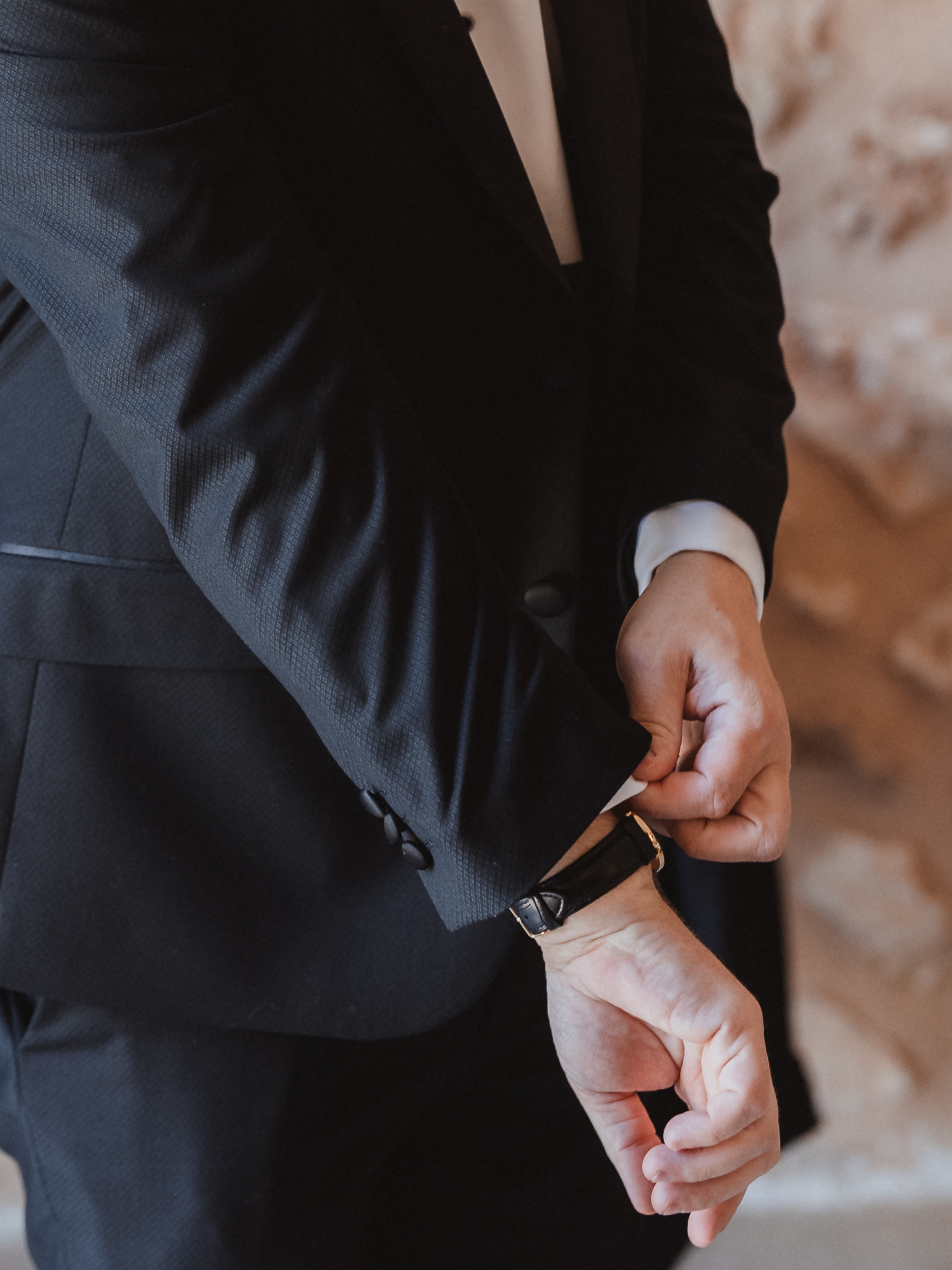 Close-up of groom adjusting jacket sleeves during wedding preparations in Mallorca